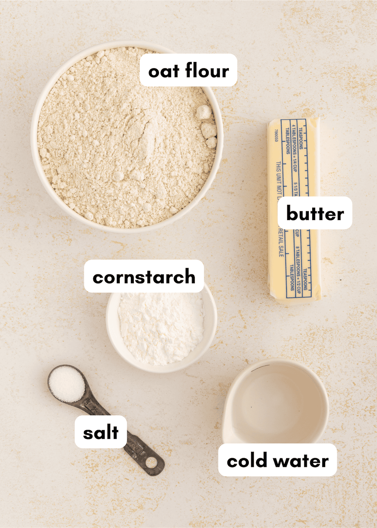 Oat flour, butter, cornstarch, salt, and cold water labeled and arranged on a light surface.