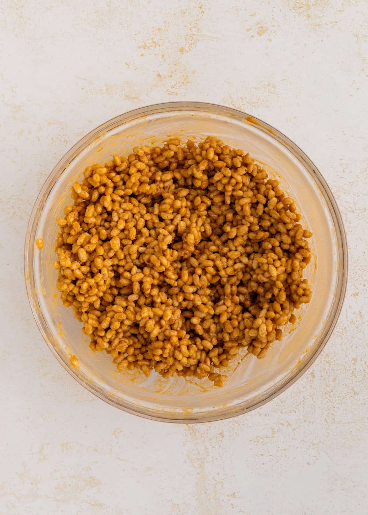 A glass bowl filled with crispy rice cereal coated in a brown mixture.