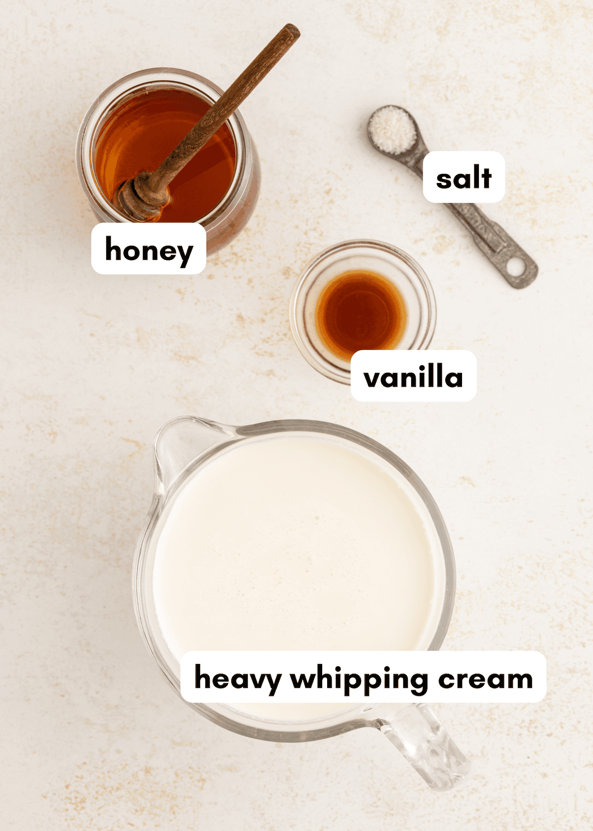 Honey whipped cream, salt, and vanilla in labeled containers on a white surface.
