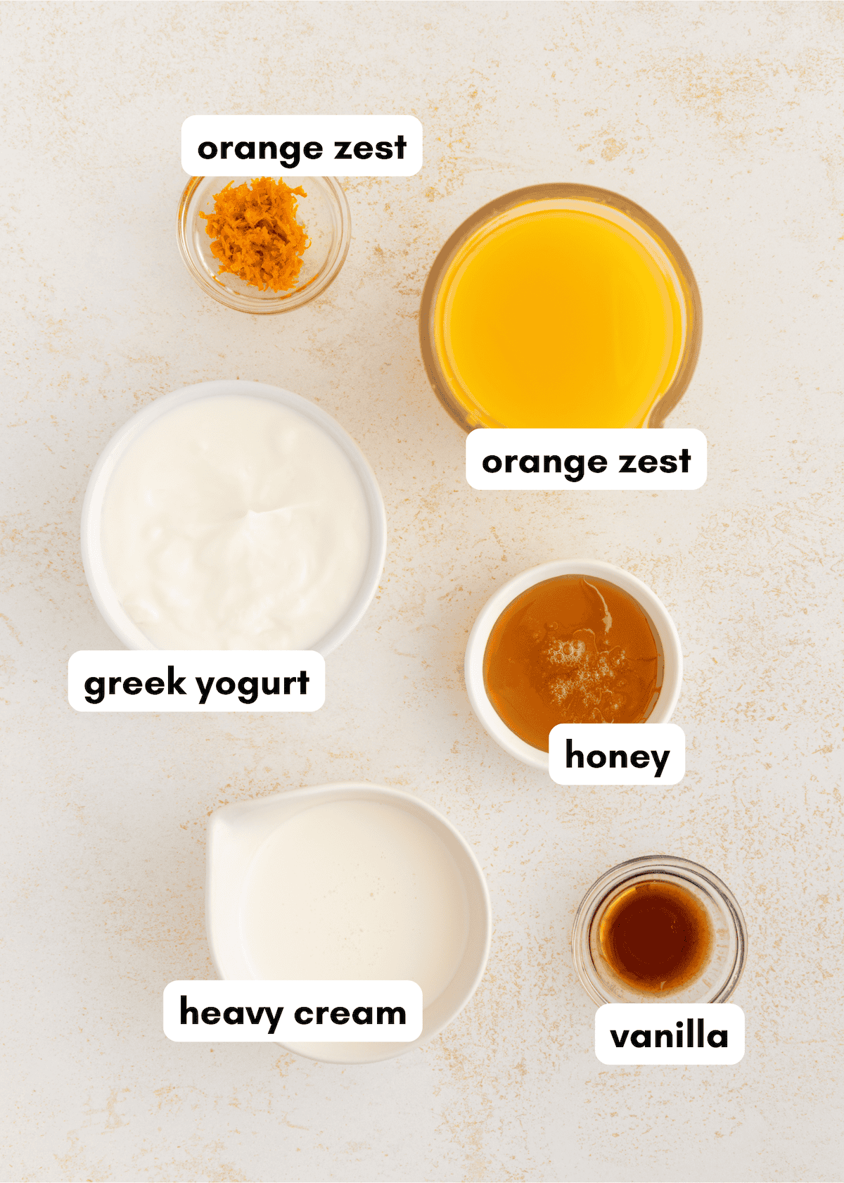 Six labeled bowls with orange zest, orange juice, Greek yogurt, honey, heavy cream, and vanilla.