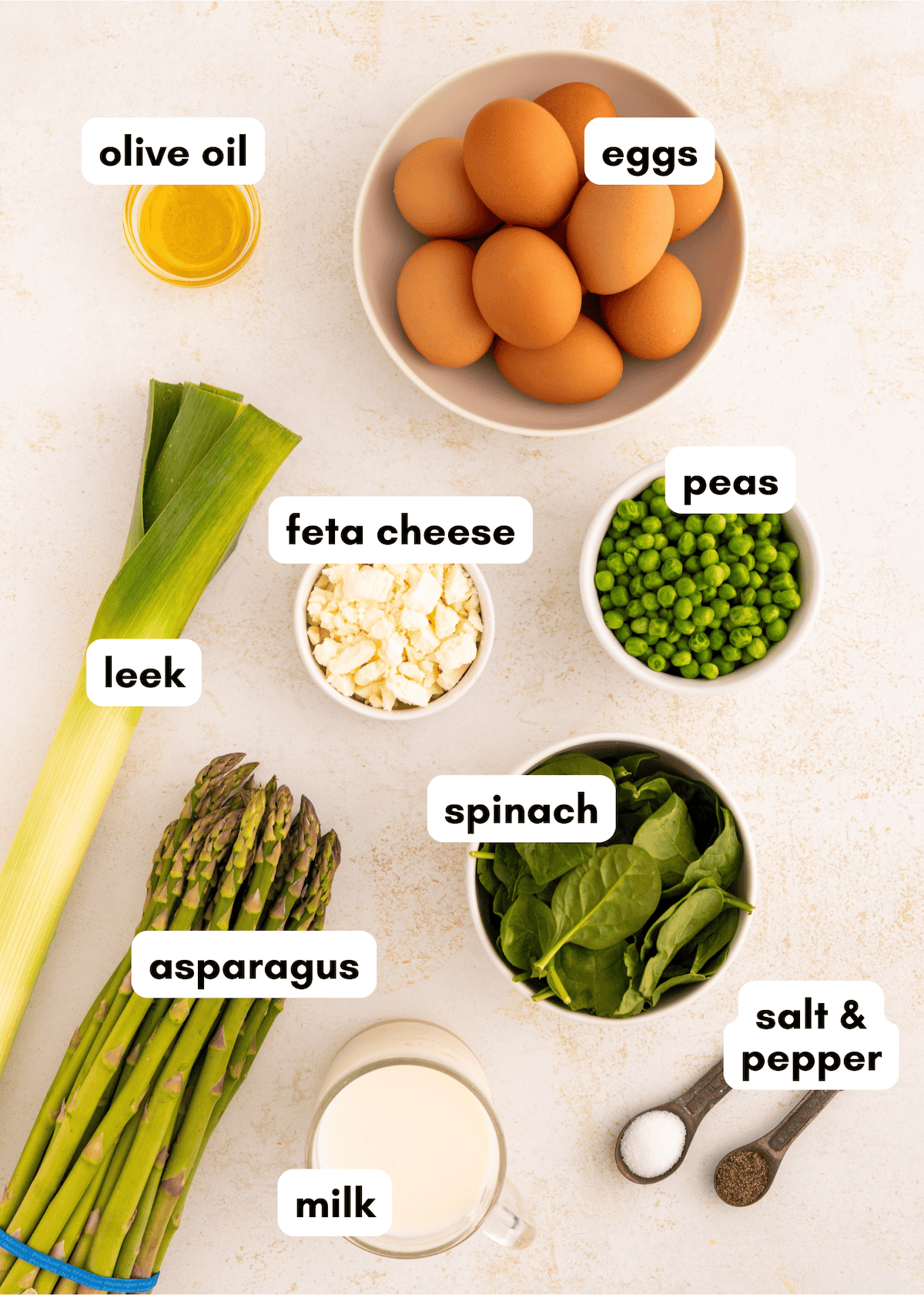 Spring vegetable frittata with eggs, feta, asparagus, peas, and spinach on a table.