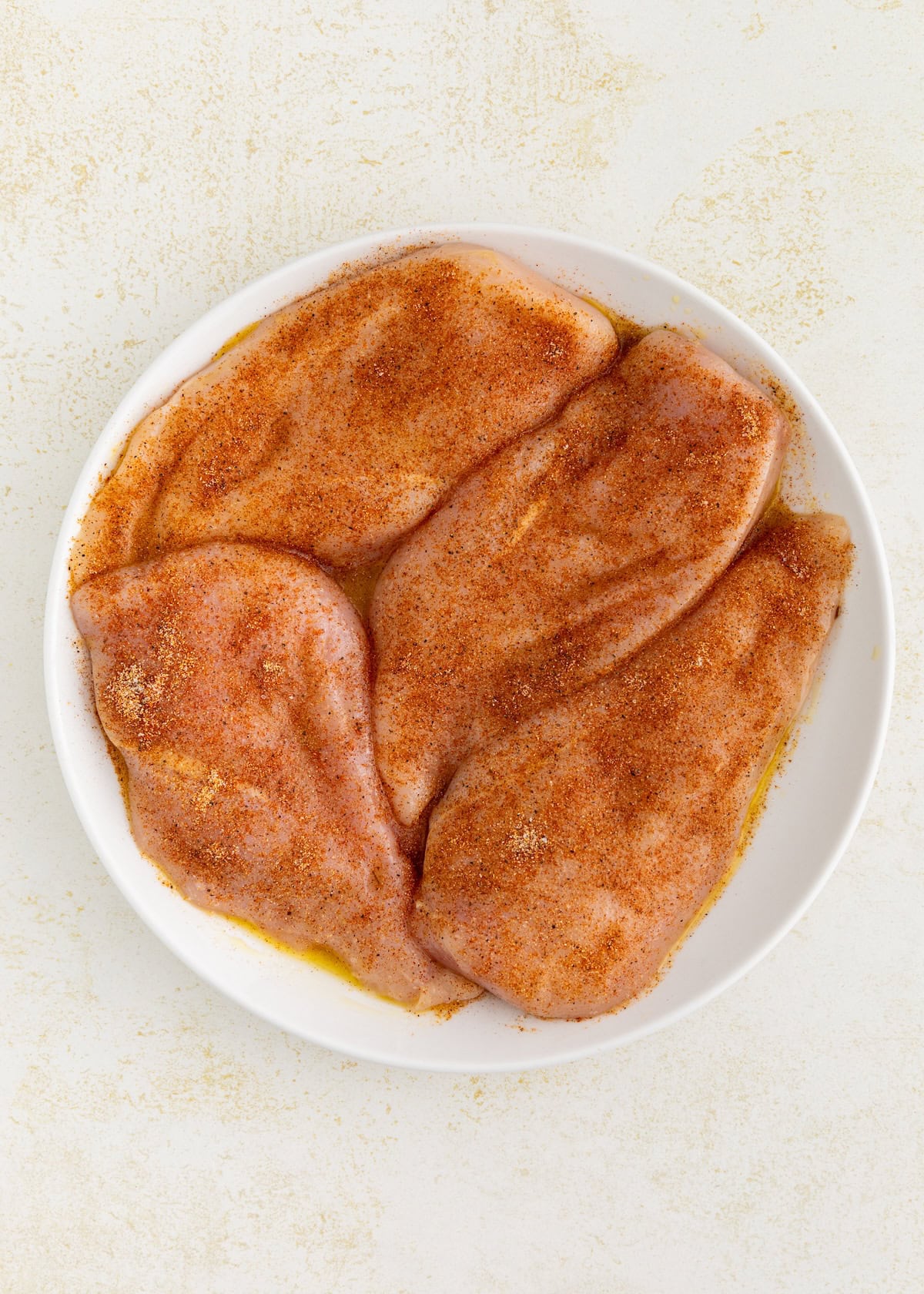 Air Fryer Grilled Chicken breasts coated with seasoning on a white plate.