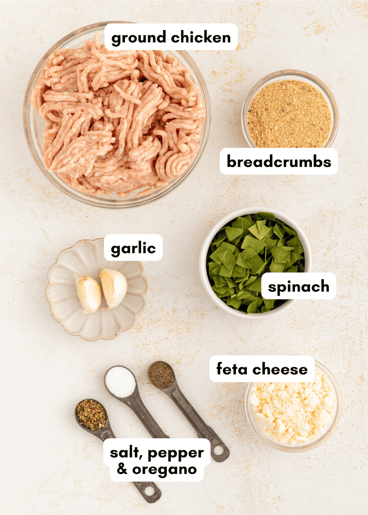 Chicken feta burgers ingredients-ground chicken, breadcrumbs, spinach, garlic, and spices in bowls.