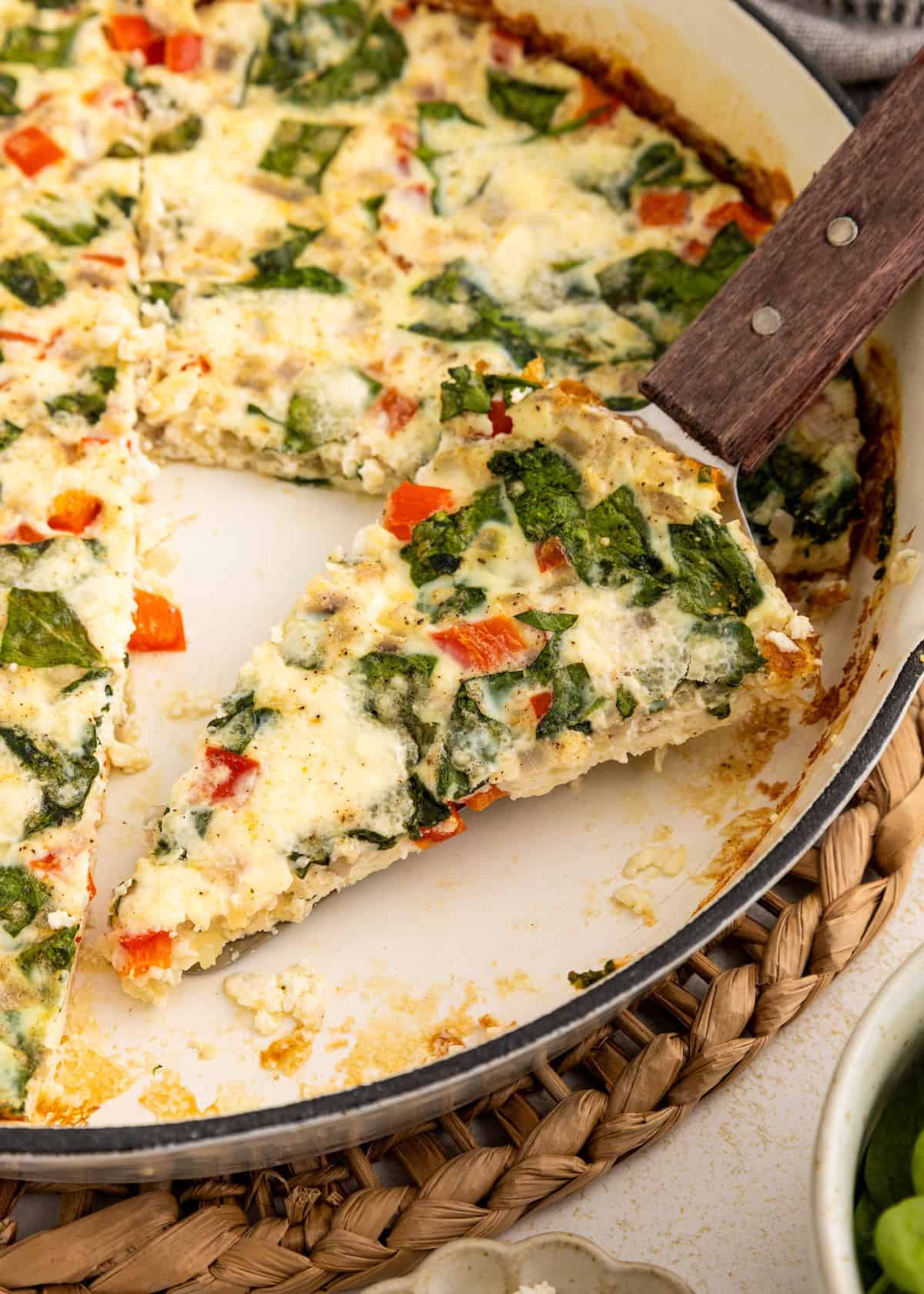 A slice of vegetable frittata being served from a pan.