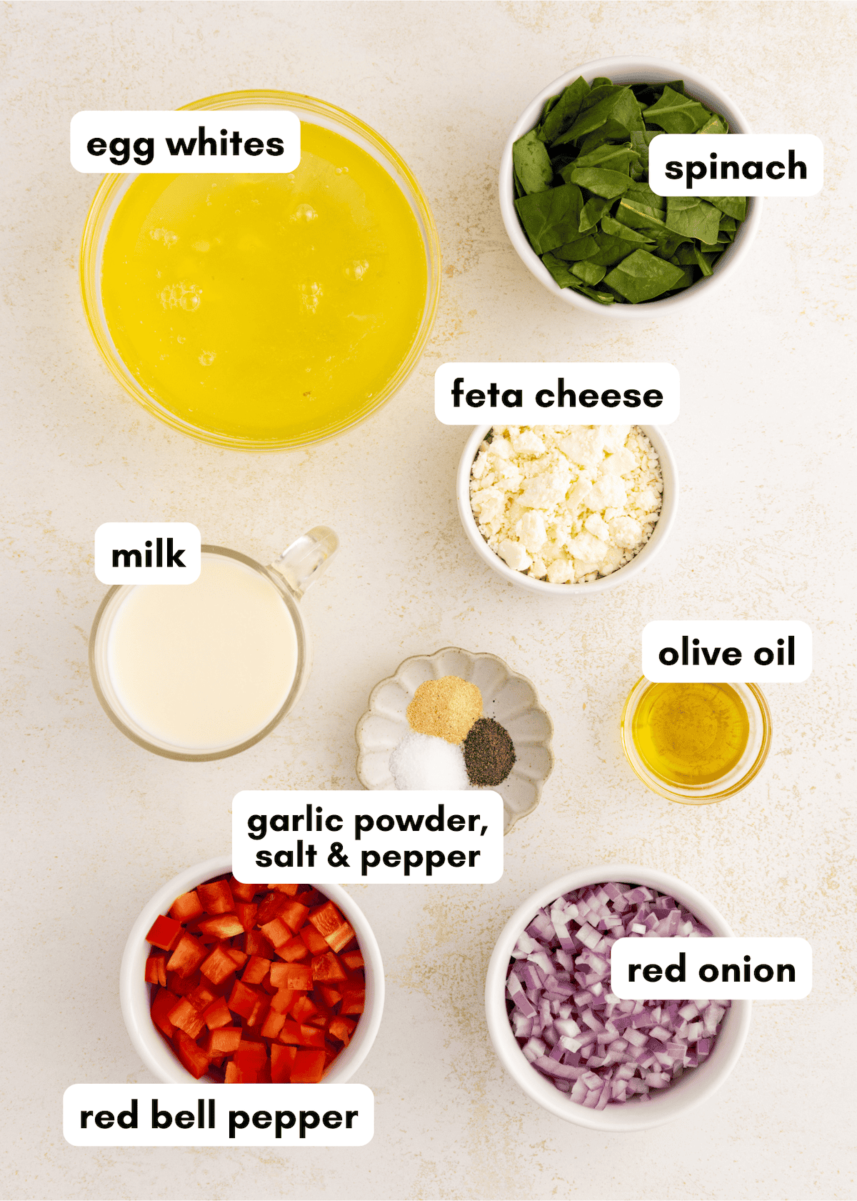 Ingredients for an omelet: egg whites, spinach, feta, milk, olive oil, seasonings, peppers, onion.