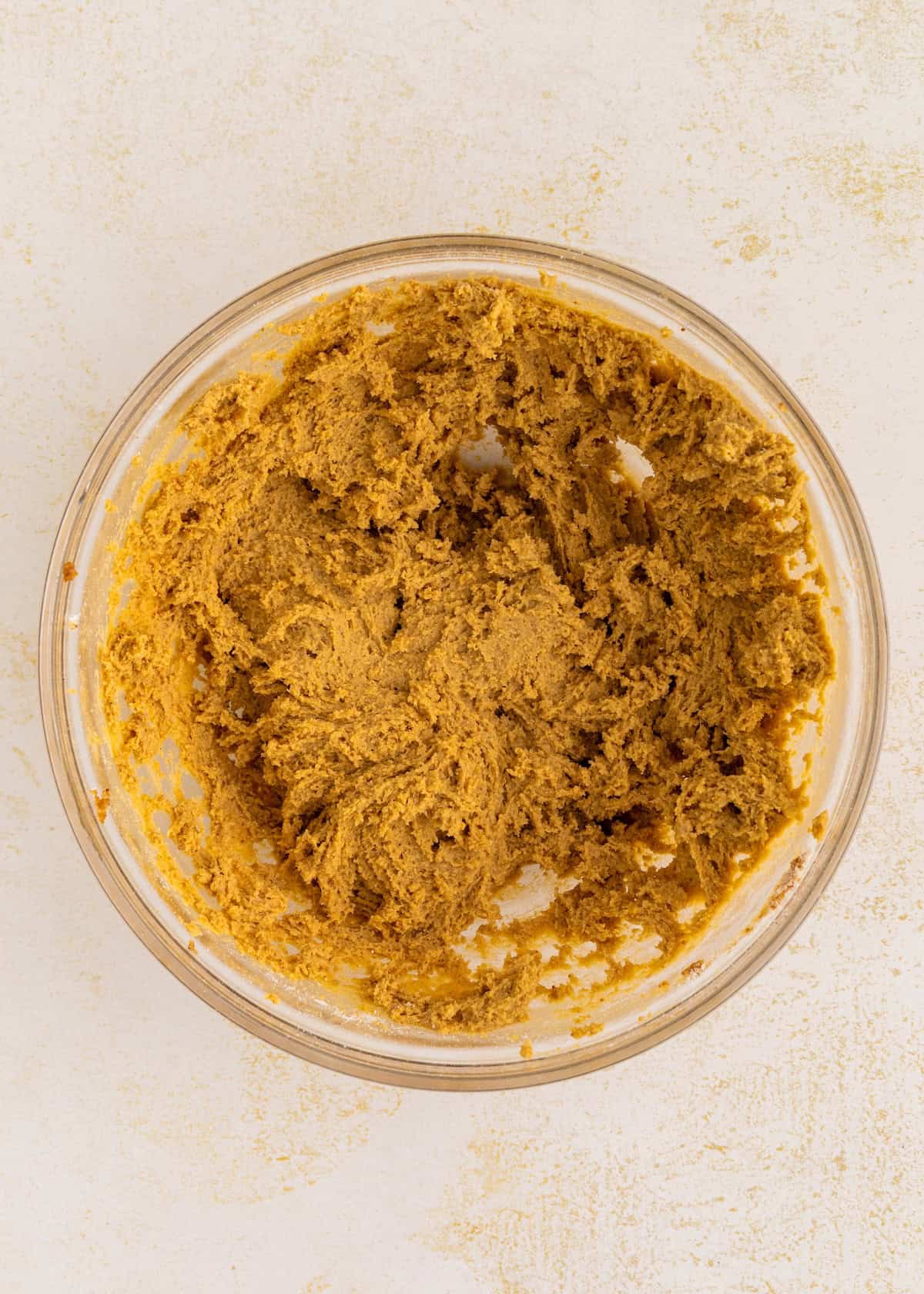 A glass bowl filled with gluten-free thumbprint cookie dough on a light-colored surface.