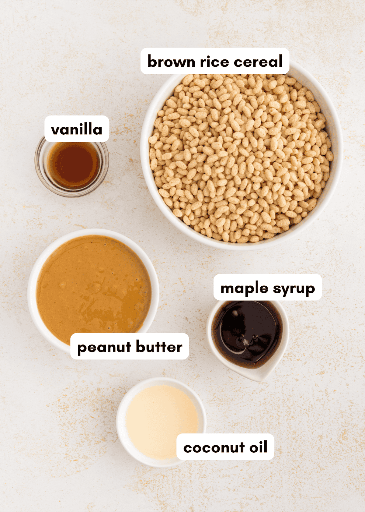 Ingredients in bowls for healthy rice crispy treats: brown rice cereal, peanut butter, maple syrup, coconut oil, vanilla.
