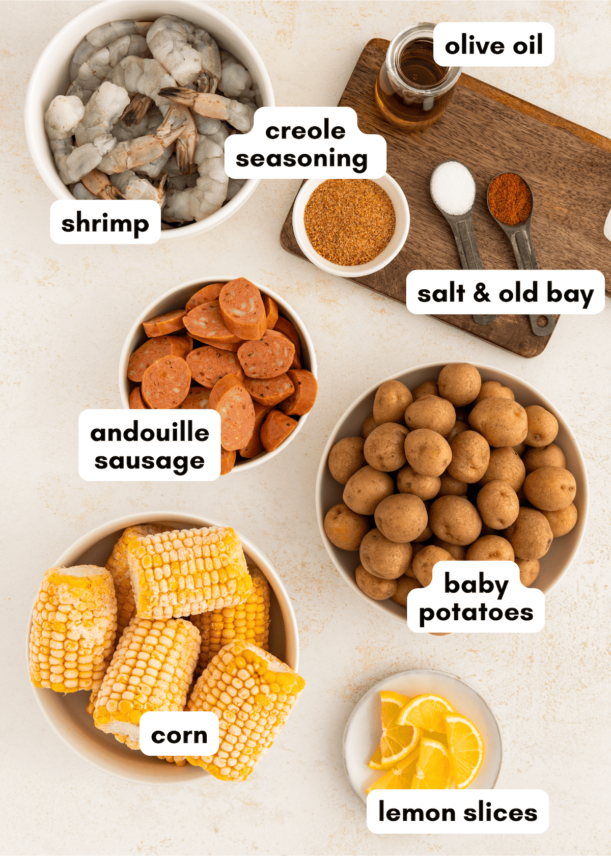 Sheet pan shrimp boil with sausage, potatoes, corn, lemon slices, and savory seasoning.
