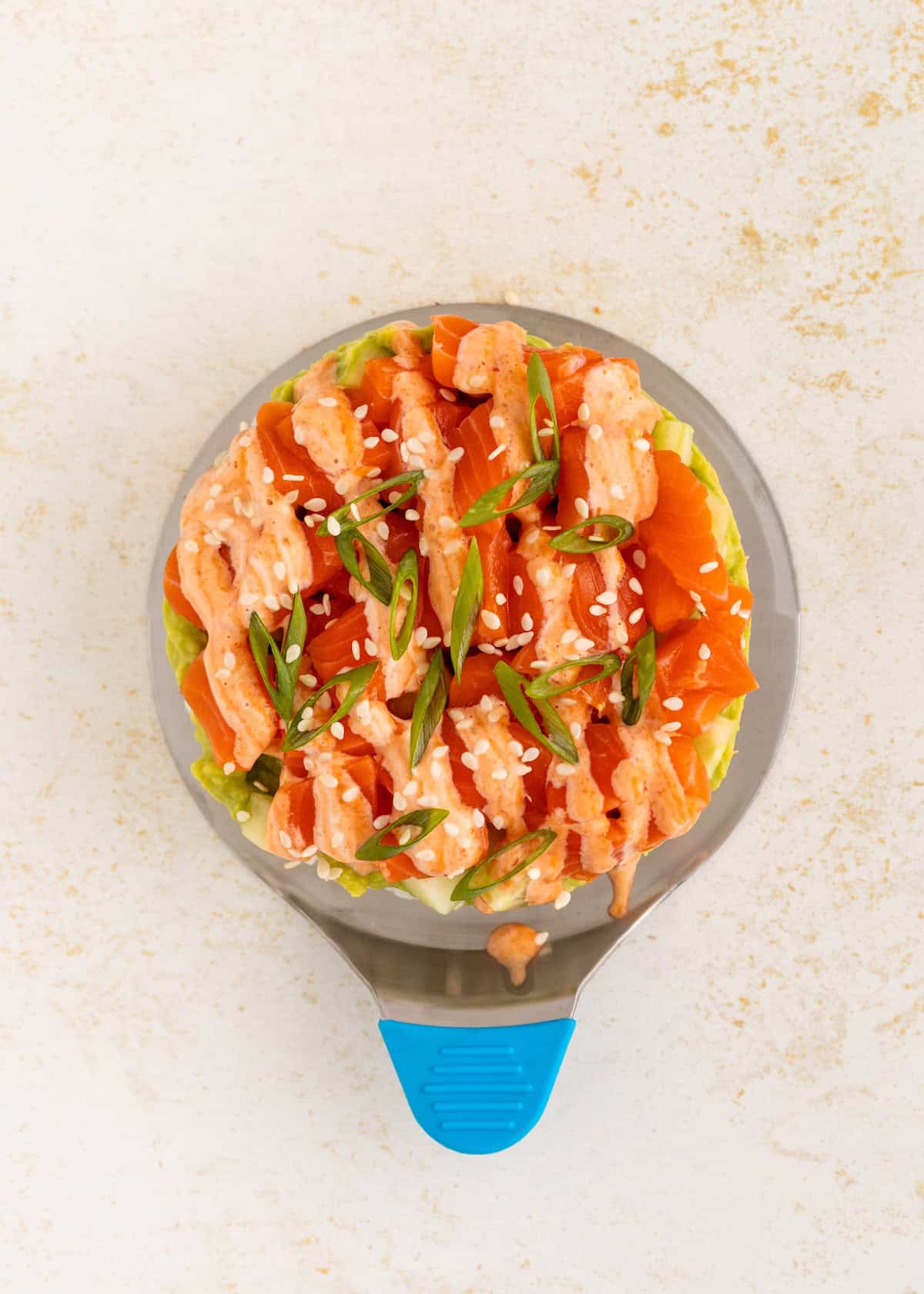 Overhead view of sushi stacks bake topped with spicy mayo, green onions, and sesame seeds.