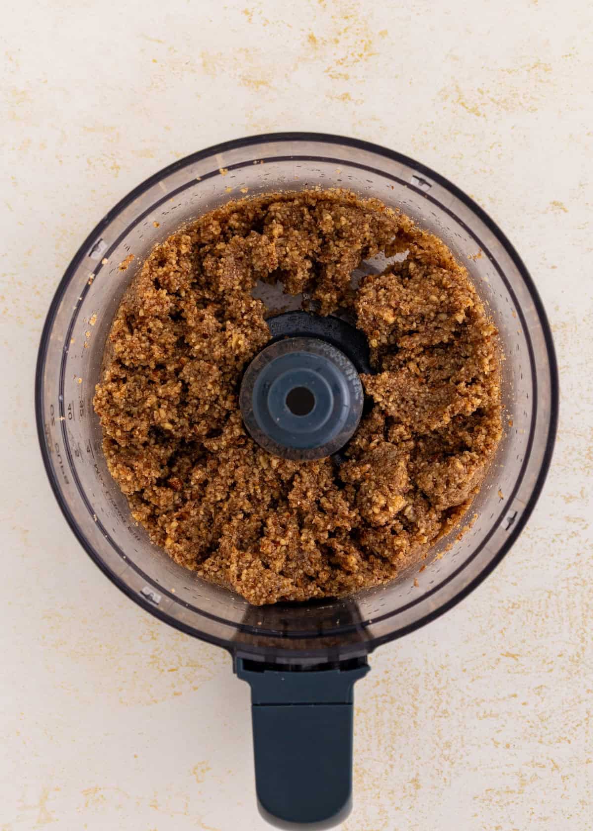 Brown crumbly mixture for sweet potato pie bars in a food processor viewed from above.