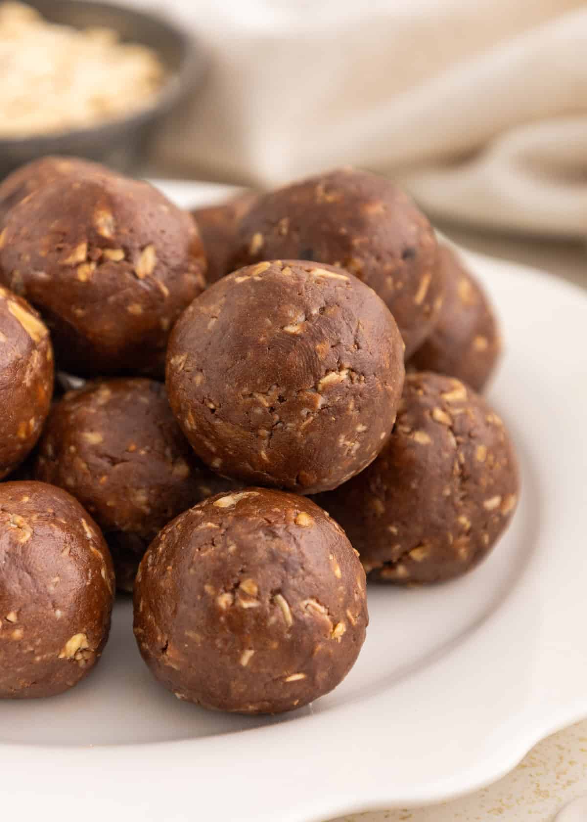 A plate of chocolate oat energy balls stacked on top of each other.