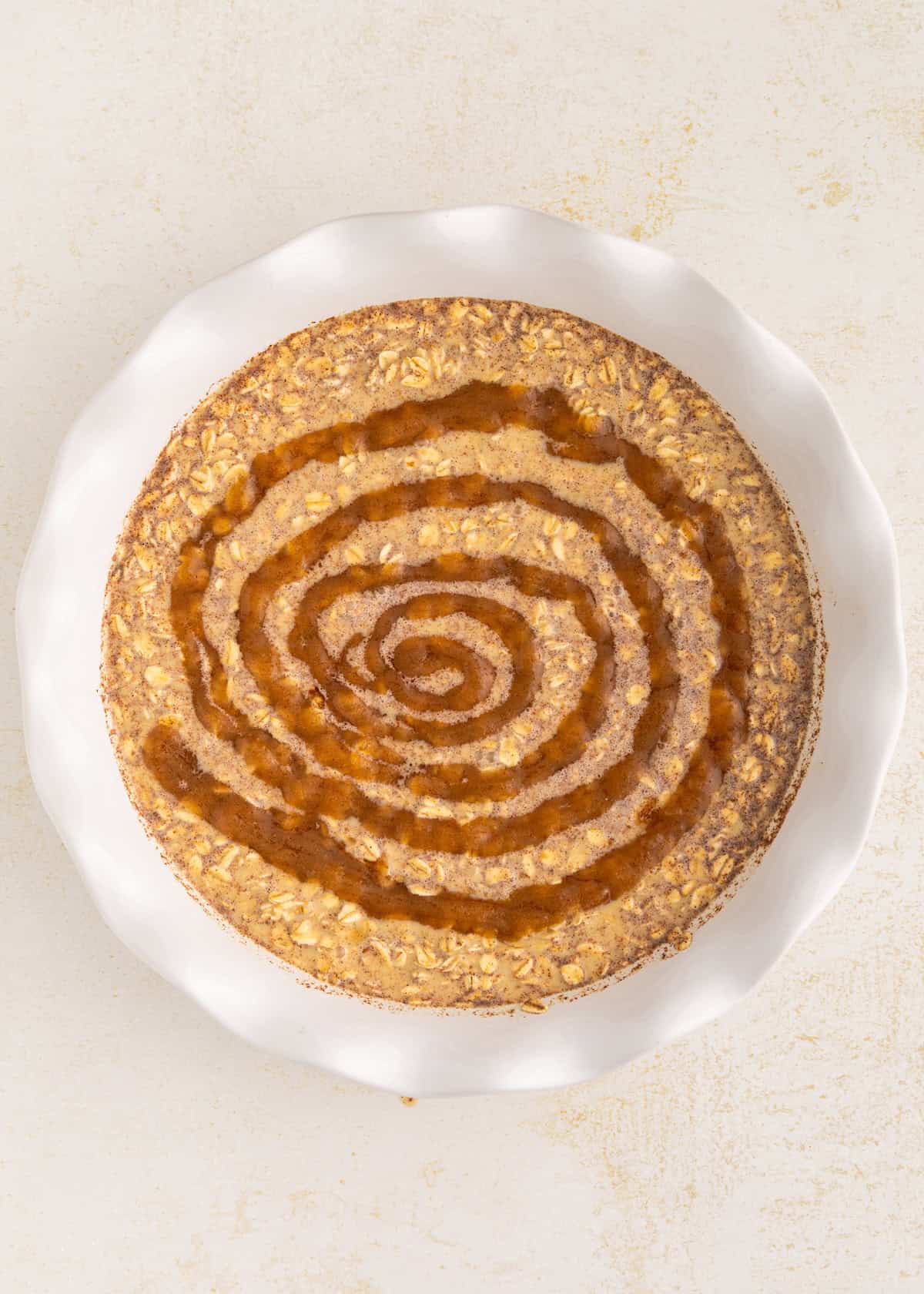 Round cake with a spiral pattern on top, displayed on a white plate against a light background.