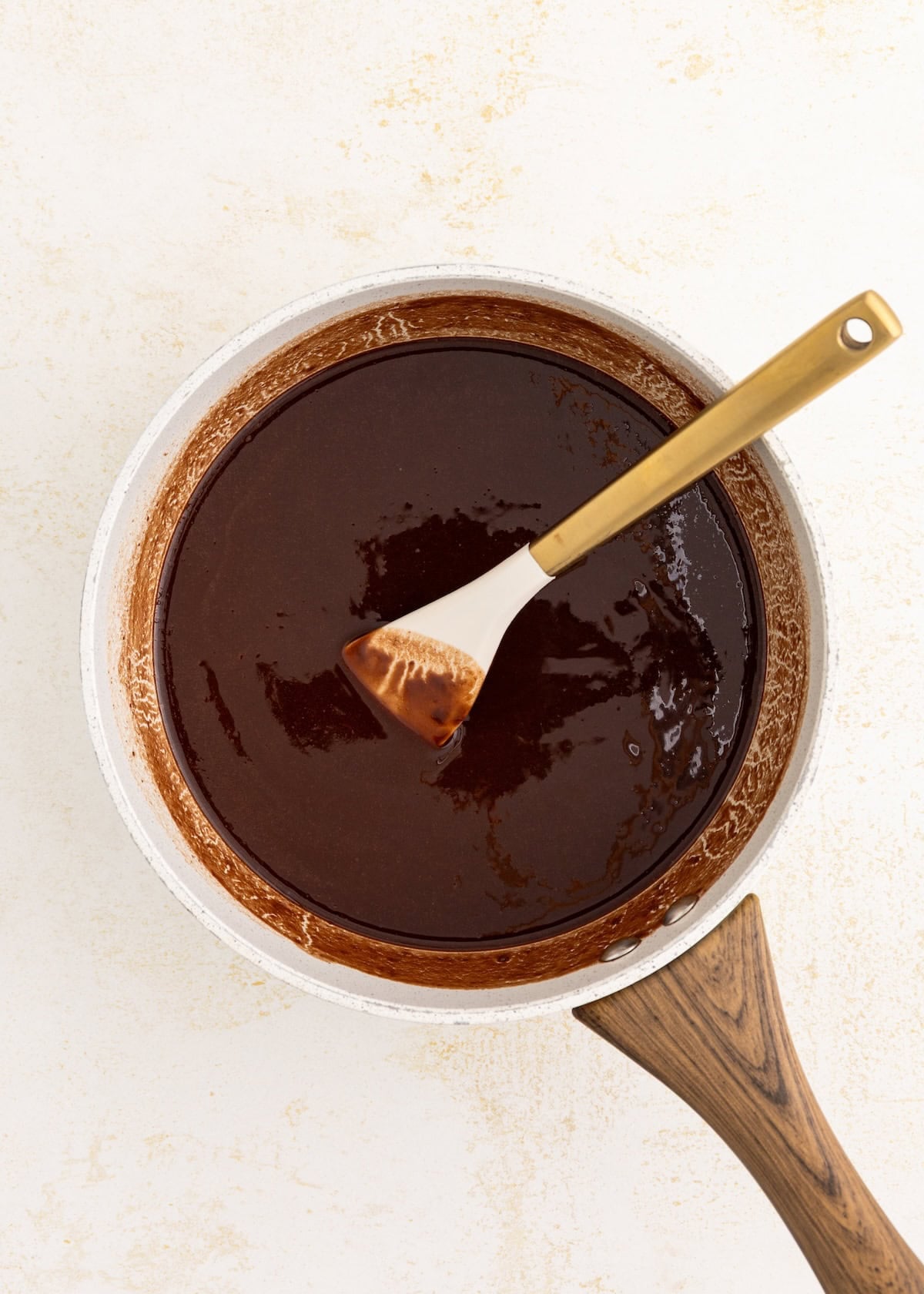A saucepan of melted chocolate with a spatula resting on the side.