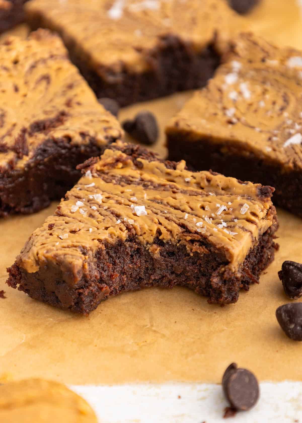 A brownie with a peanut butter swirl and a bite taken out, topped with flaky sea salt.