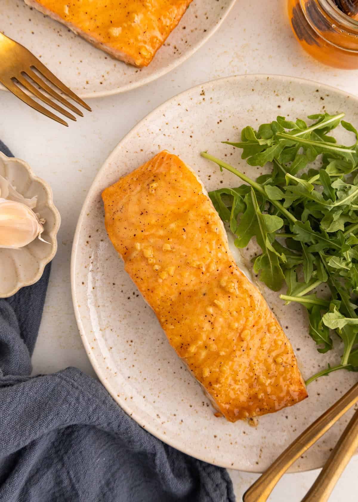 A plate with baked salmon and a side of fresh arugula greens.
