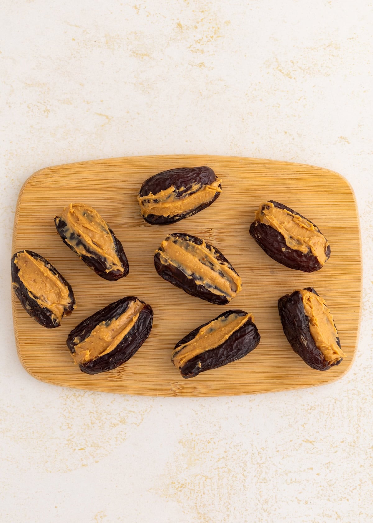 Peanut butter filled dates on a cutting board.