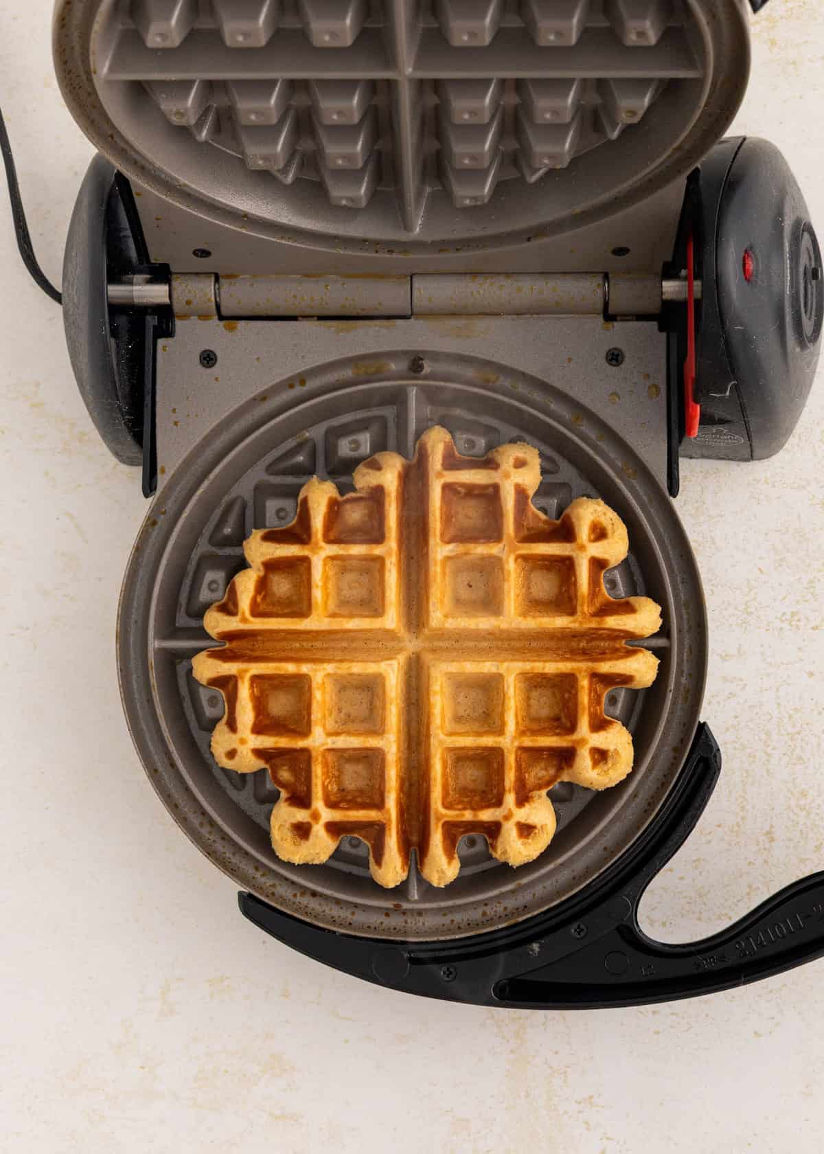 A golden waffle inside an open waffle maker, viewed from above.