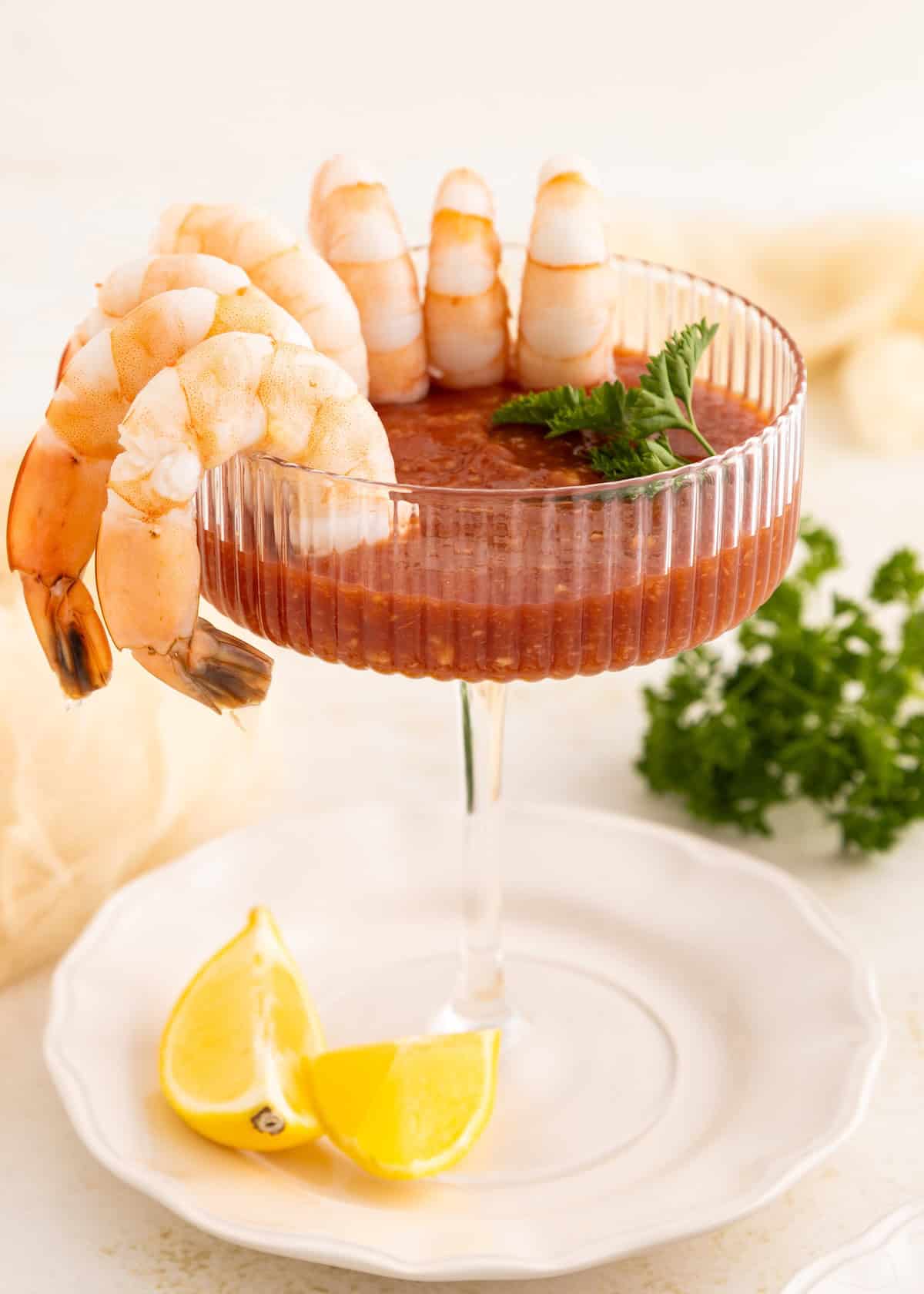 Shrimp cocktail in a glass with cocktail sauce, lemon wedges, and parsley garnish.