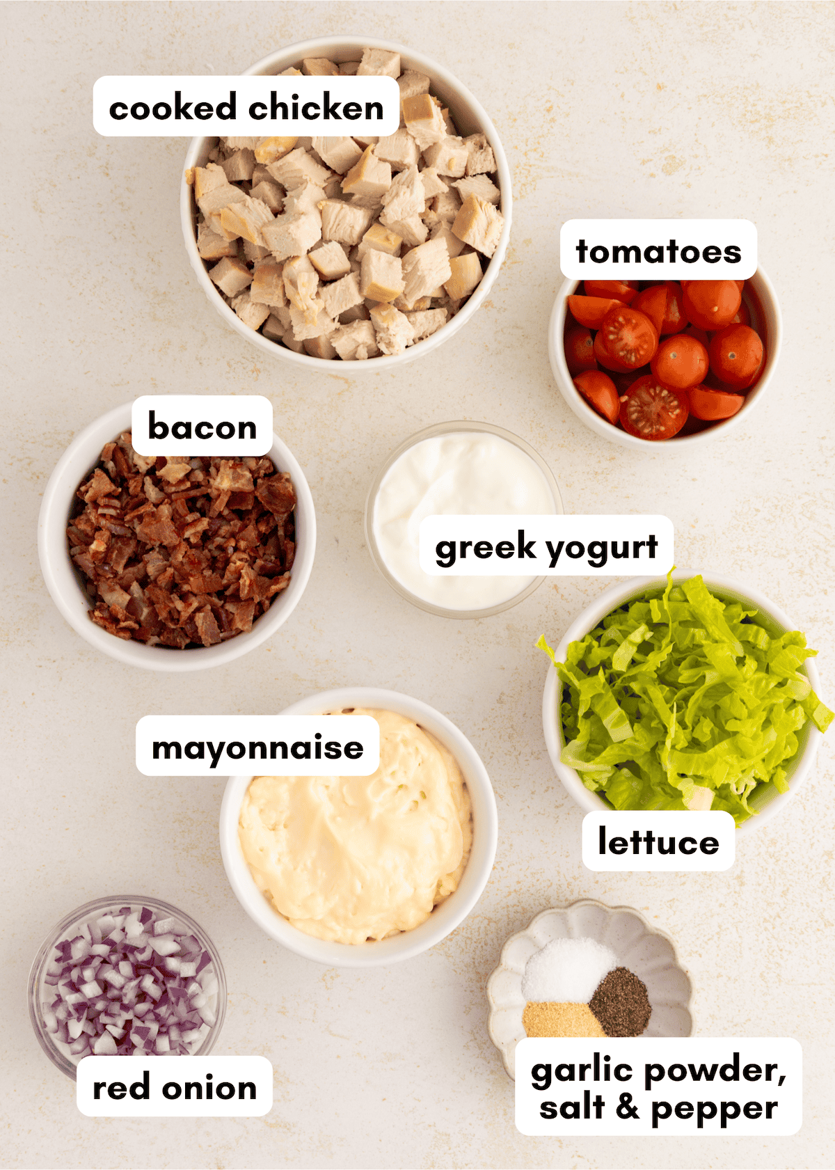 Seven bowls of BLT Chicken Salad with chicken, bacon, tomatoes, mayo, yogurt, lettuce, and spices.