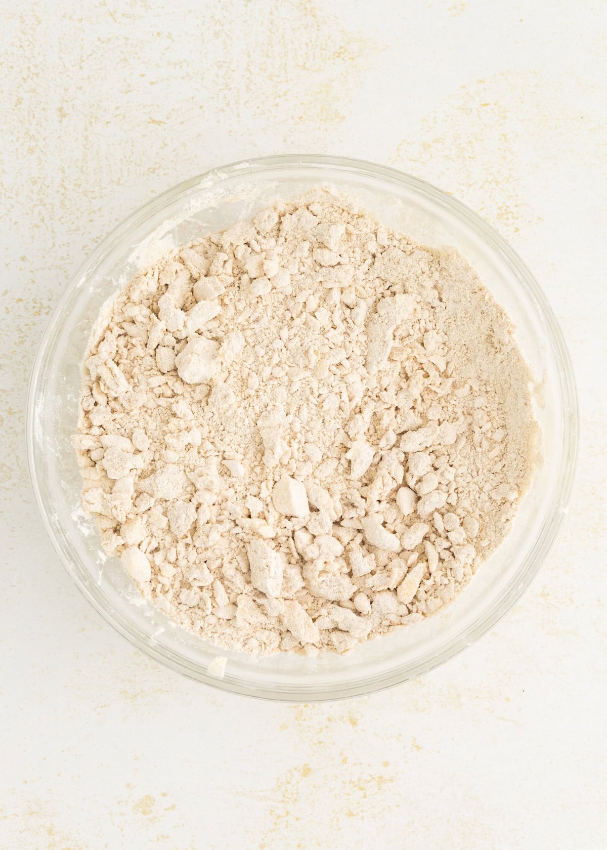 Bowl of crumbly flour mixture on a light-colored surface.
