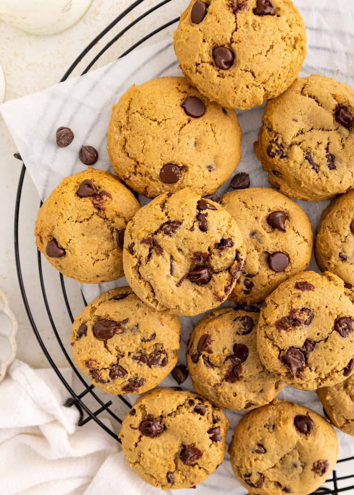 Chocolate chip cookies arranged on a cooling rack with parchment paper.