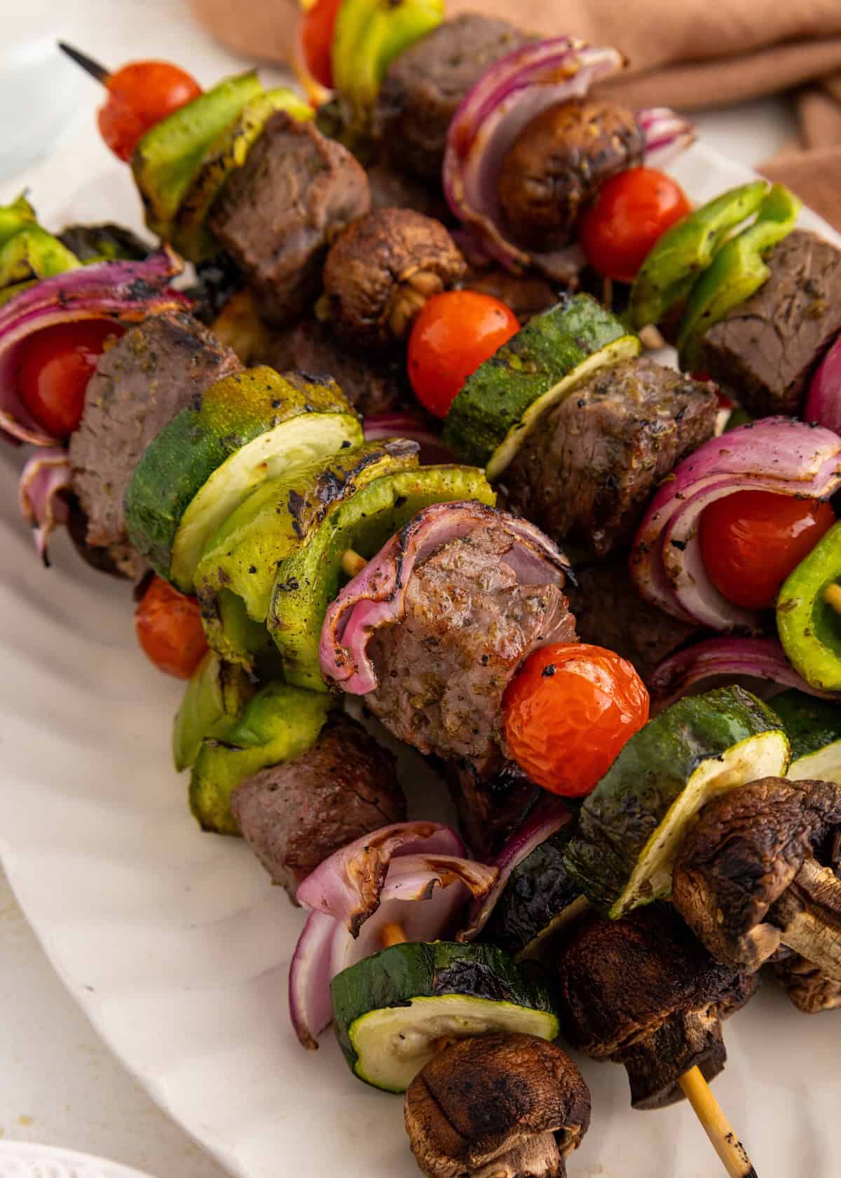 Grilled beef kebabs with cherry tomatoes, mushrooms, zucchini, red onion, and green bell pepper.