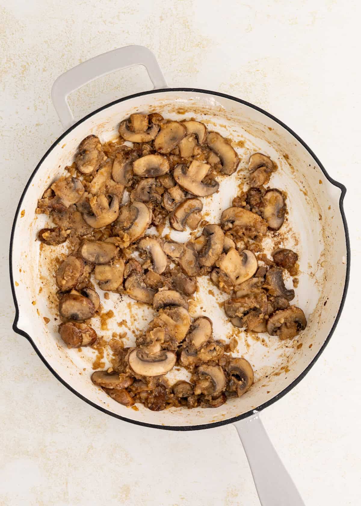 Sautéed mushrooms and onions, perfect for Salisbury Steak with Mushroom Gravy, in a white skillet.