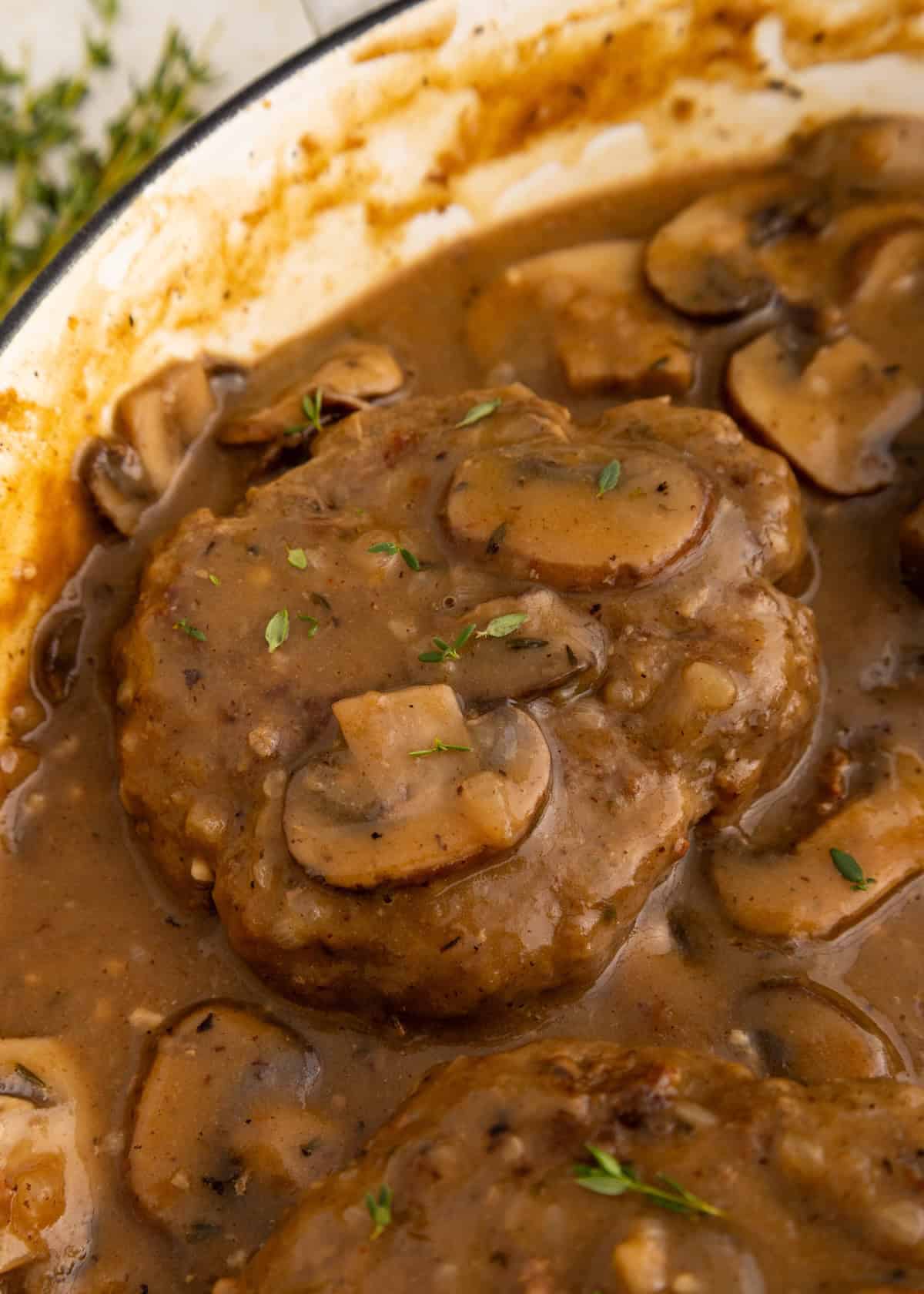 Salisbury Steak with Mushroom Gravy, garnished with fresh herbs for a classic comfort meal.