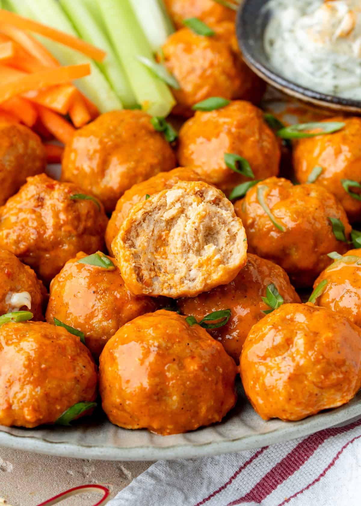 Buffalo chicken meatballs with carrot and celery sticks and a side of dip.